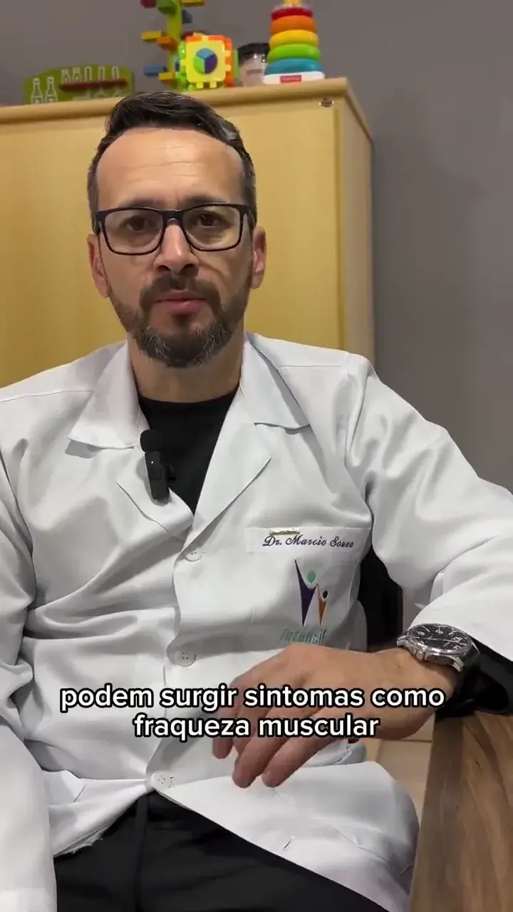 Profissional de jaleco branco sentado, falando diante da câmera. A legenda na tela diz “podem surgir sintomas como”.